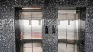 Dos puertas de ascensor con acabado metálico y una pared texturizada.