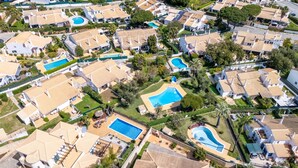 Vista aérea de una zona residencial con varias casas, piscinas y abundante vegetación.