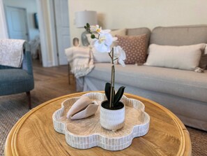 Ein runder Couchtisch aus Holz mit einer weißen Keramiktasse, die eine Topforchidee und ein dekoratives Keramikobjekt beherbergt.
