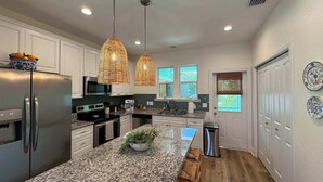 A modern kitchen with granite countertops, stainless steel appliances, and a central island. - The Orange Blossom Suite | Near UF, Shands, D-town (Gainesville)