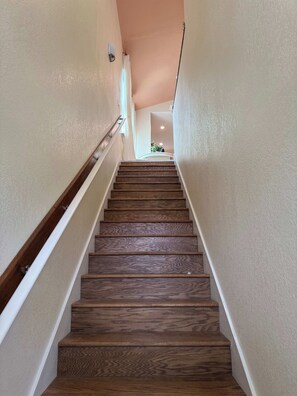 Un escalier en bois, avec des murs blancs et une main courante.
