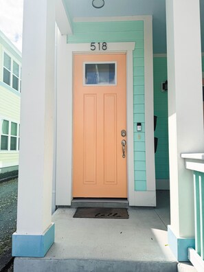 A house with a number 518 on the door, a doormat with "hello" on it, and a teal-colored exterior.