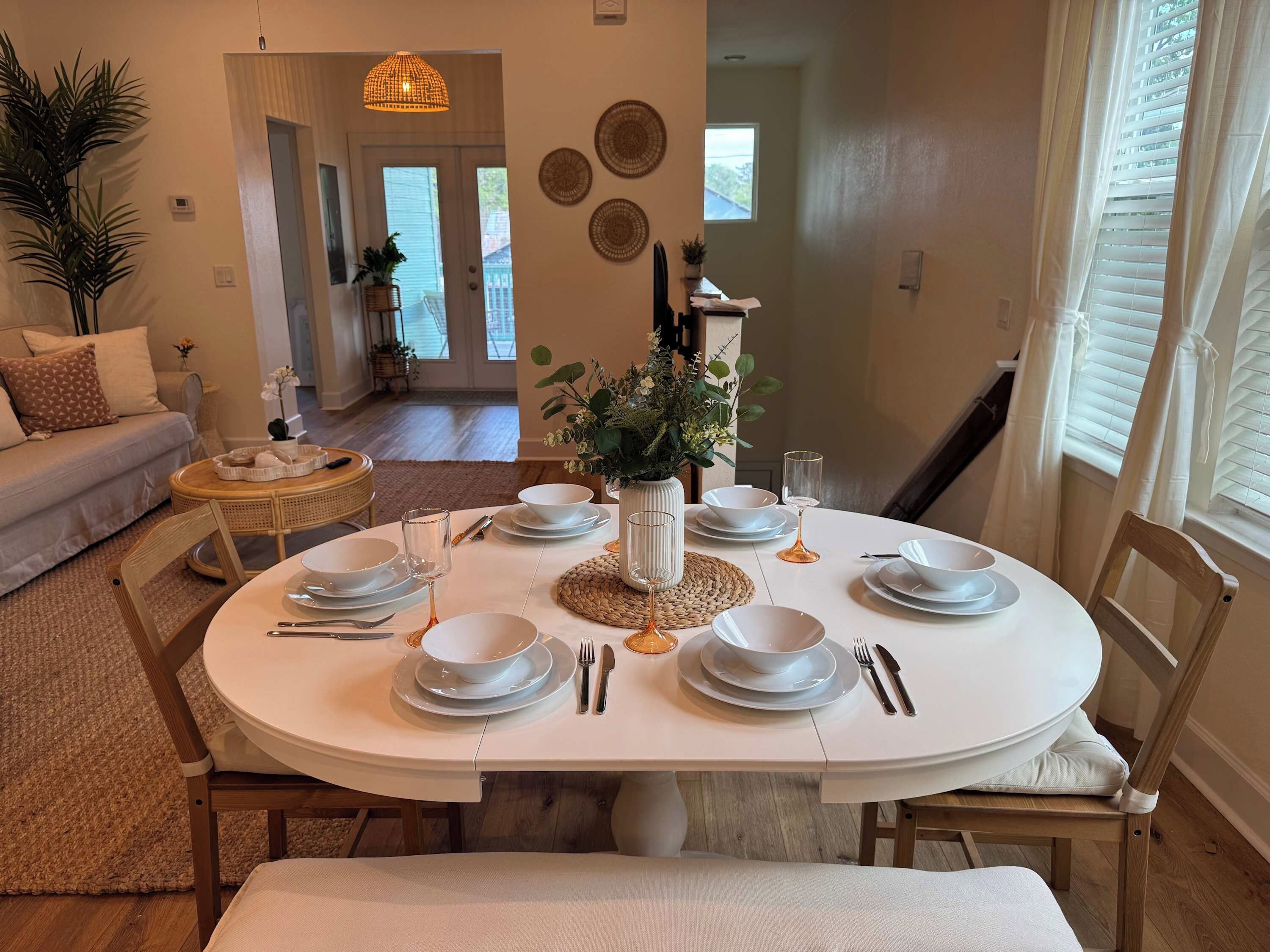A dining area with a round table set for four, surrounded by wooden chairs.