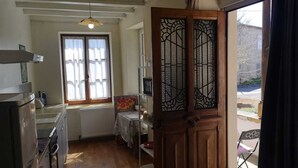 Cuina amb una porta de fusta, una finestra amb cortines i un radiador.