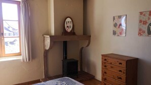 Habitació amb una llar de foc, un taulell de fusta i dues obres d'art penjades a la paret.