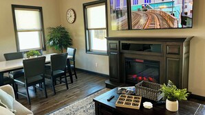 Ein Wohnzimmer mit Essbereich, Kamin und einem großen Fernseher, der eine Stadtansicht zeigt.