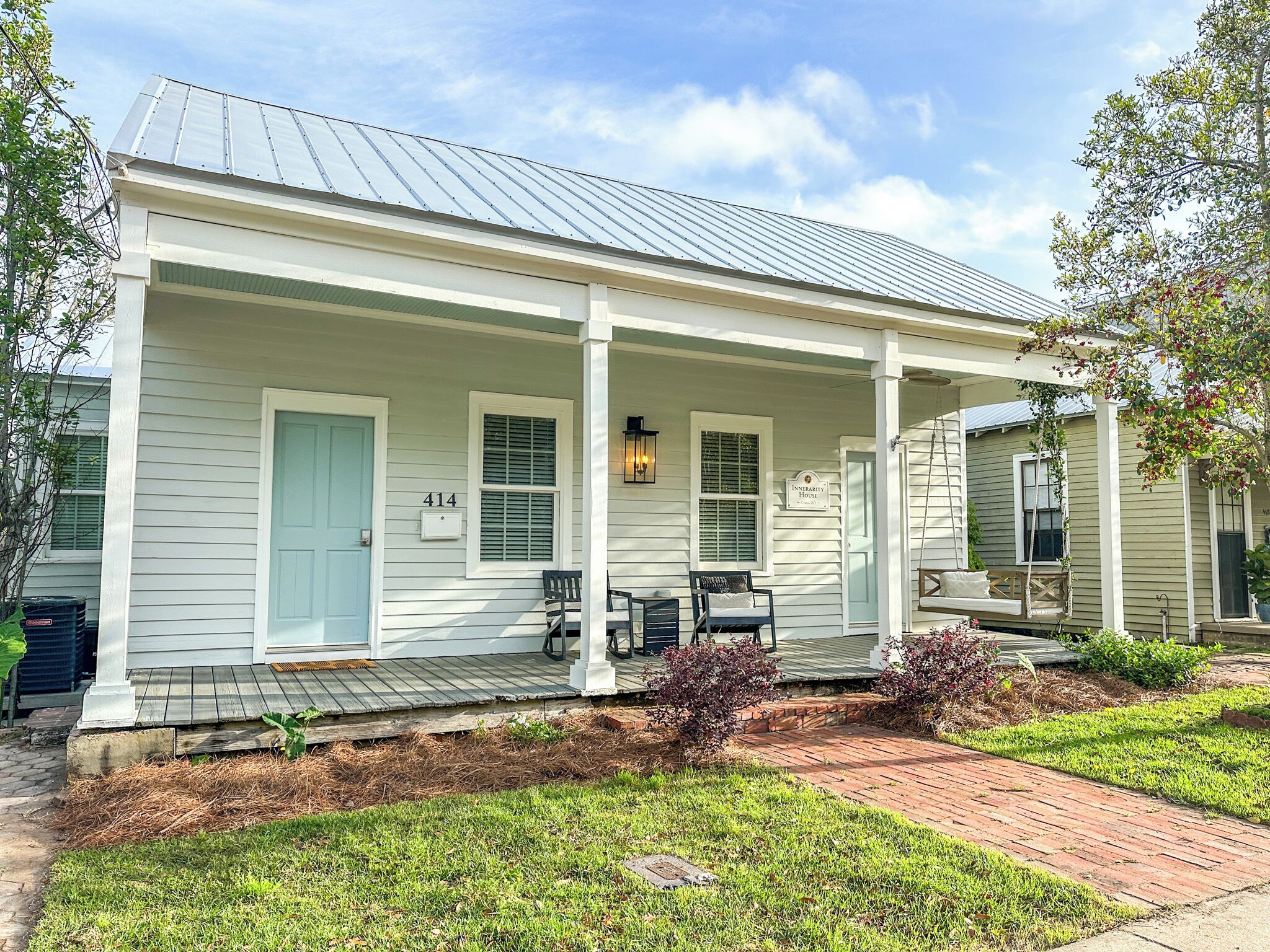 A white house with a porch, a number 414 sign, and a sign reading "Innertity House".