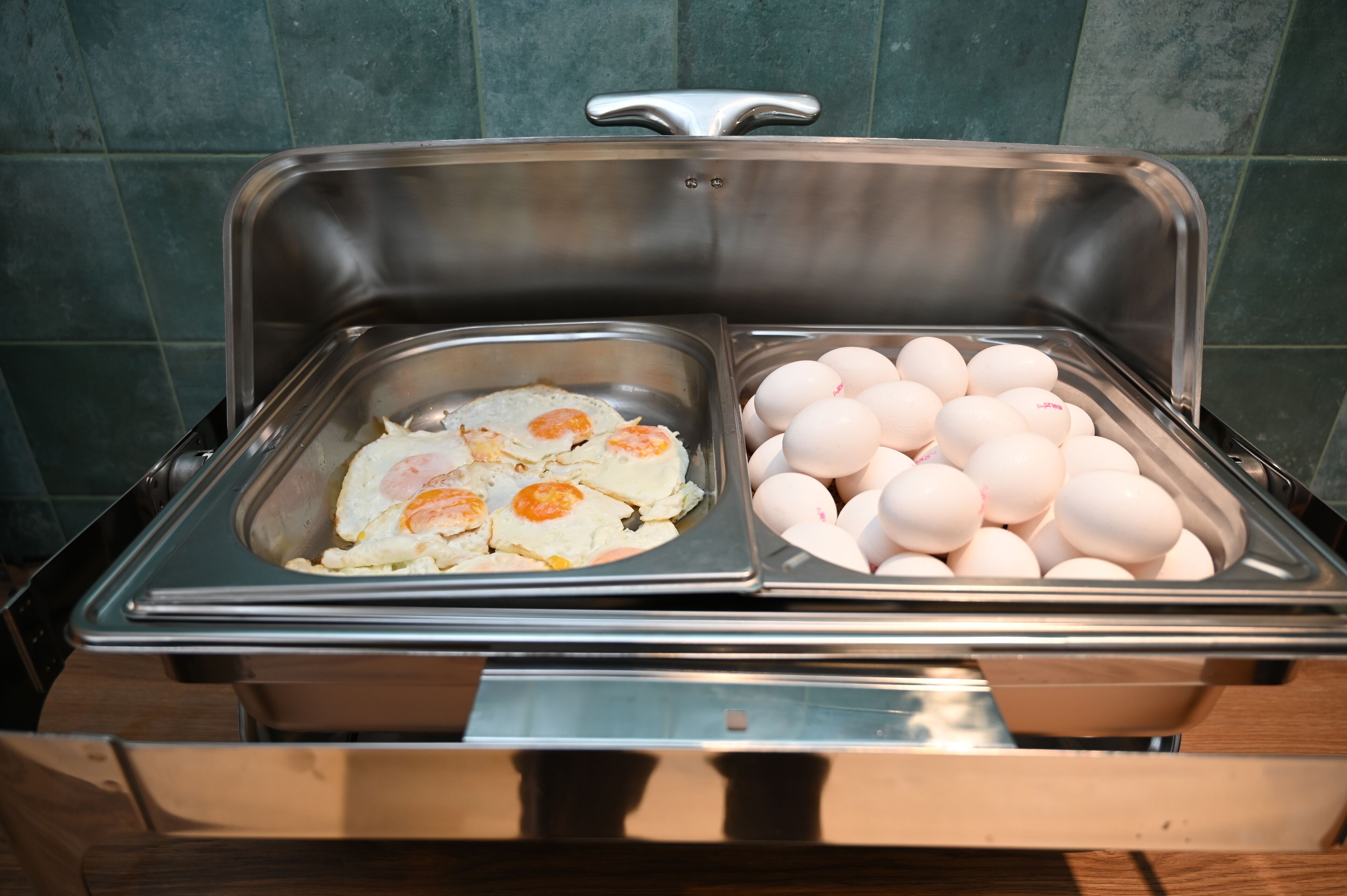 Un bufé con dos secciones: una con huevos revueltos y otra con huevos cocidos.