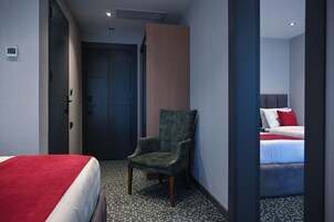 Una habitación de hotel con una cama, una silla, una puerta y una pared con un panel vertical.