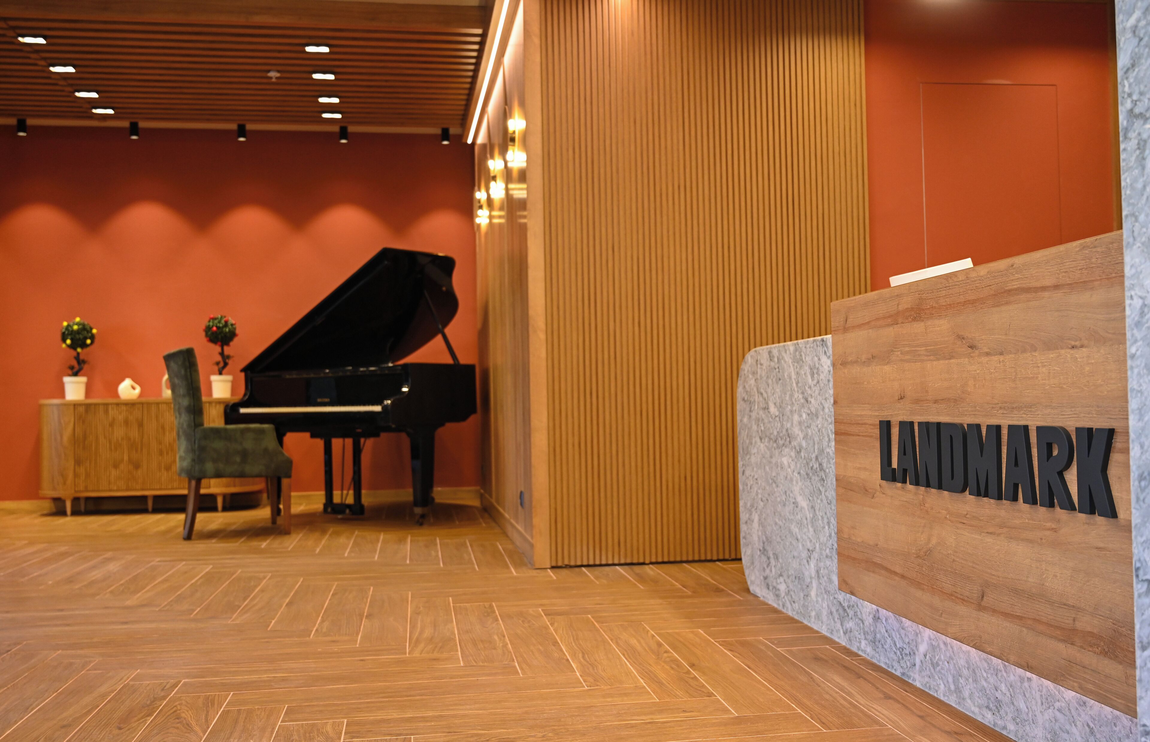 A reception area with a grand piano, a wooden reception desk, and a wall with vertical lines.