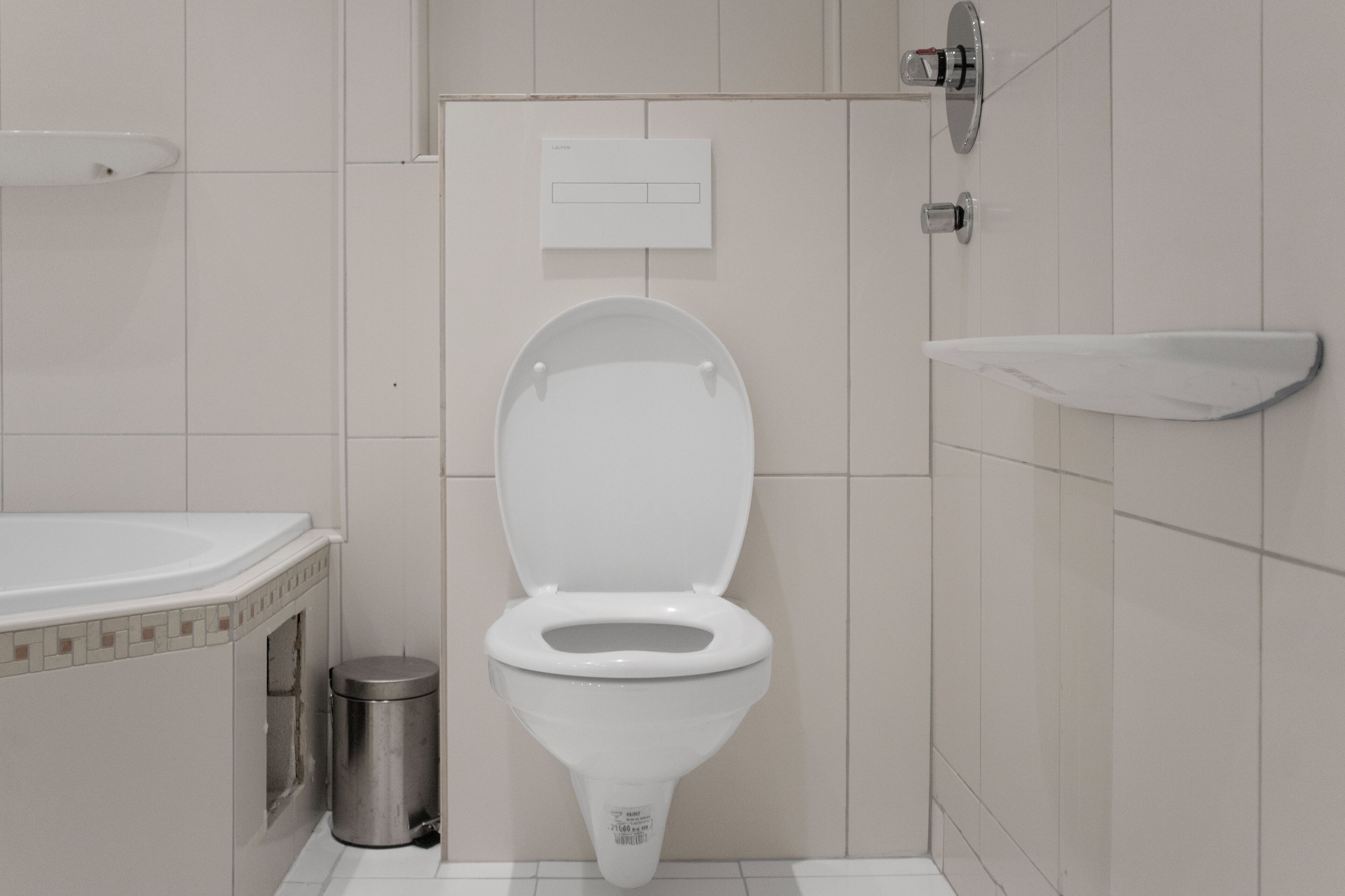 Un bagno moderno con il water bianco, un piccolo cestino e un portasapone a parete.