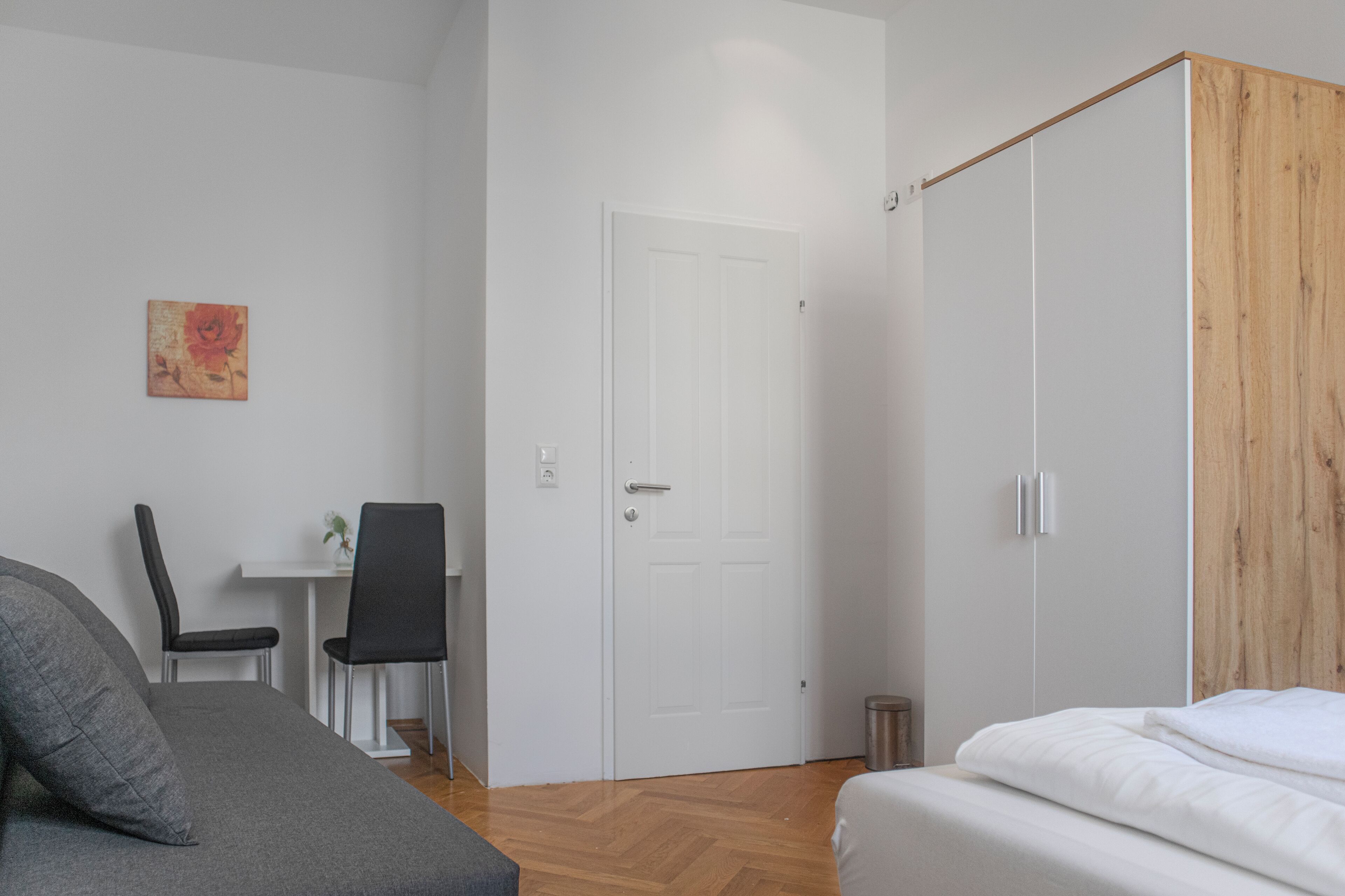 Een moderne slaapkamer met een grijze bank, een houten garderobe en een witte deur.