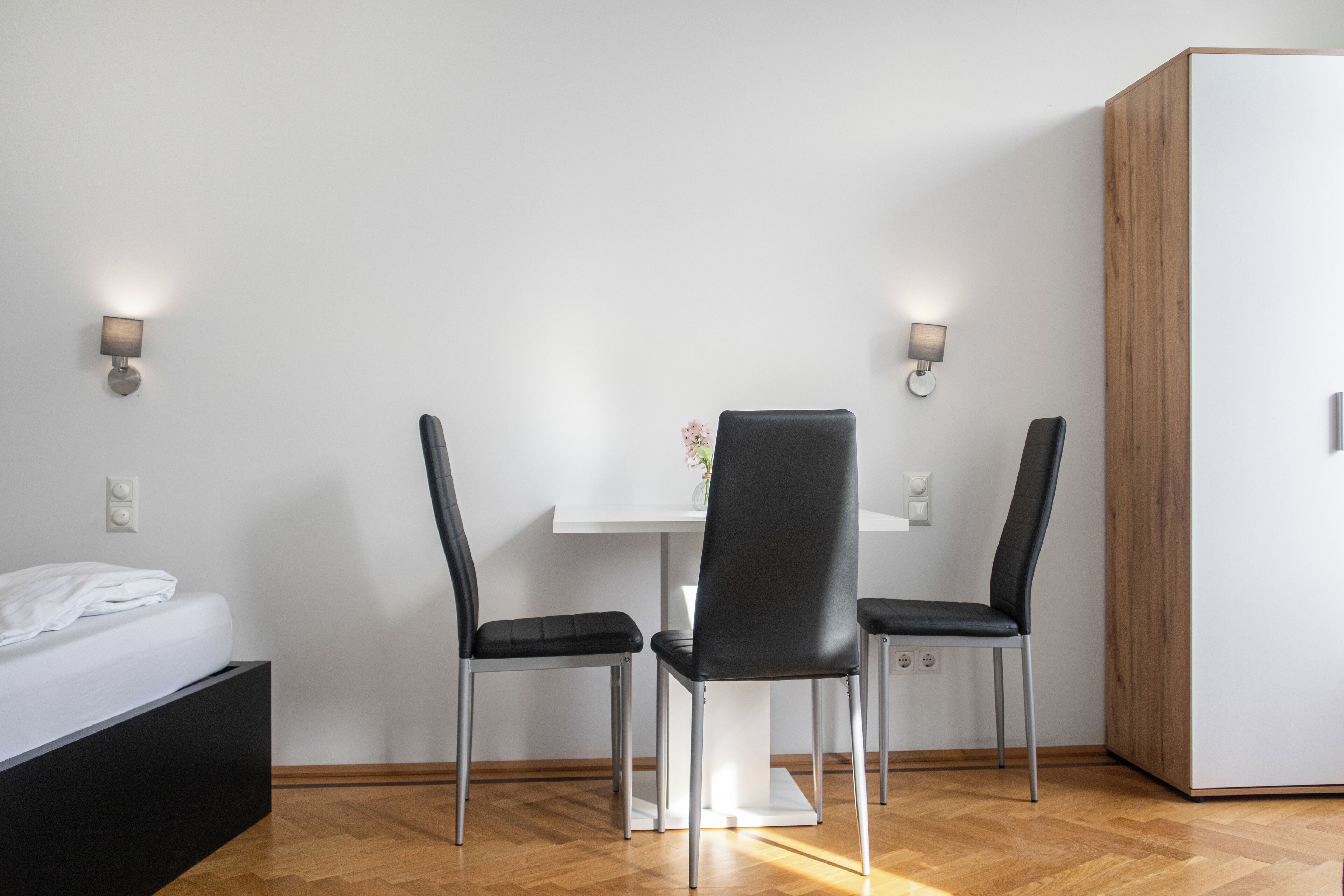 Una habitación de hotel moderna con cama, escritorio, dos sillas y armario.