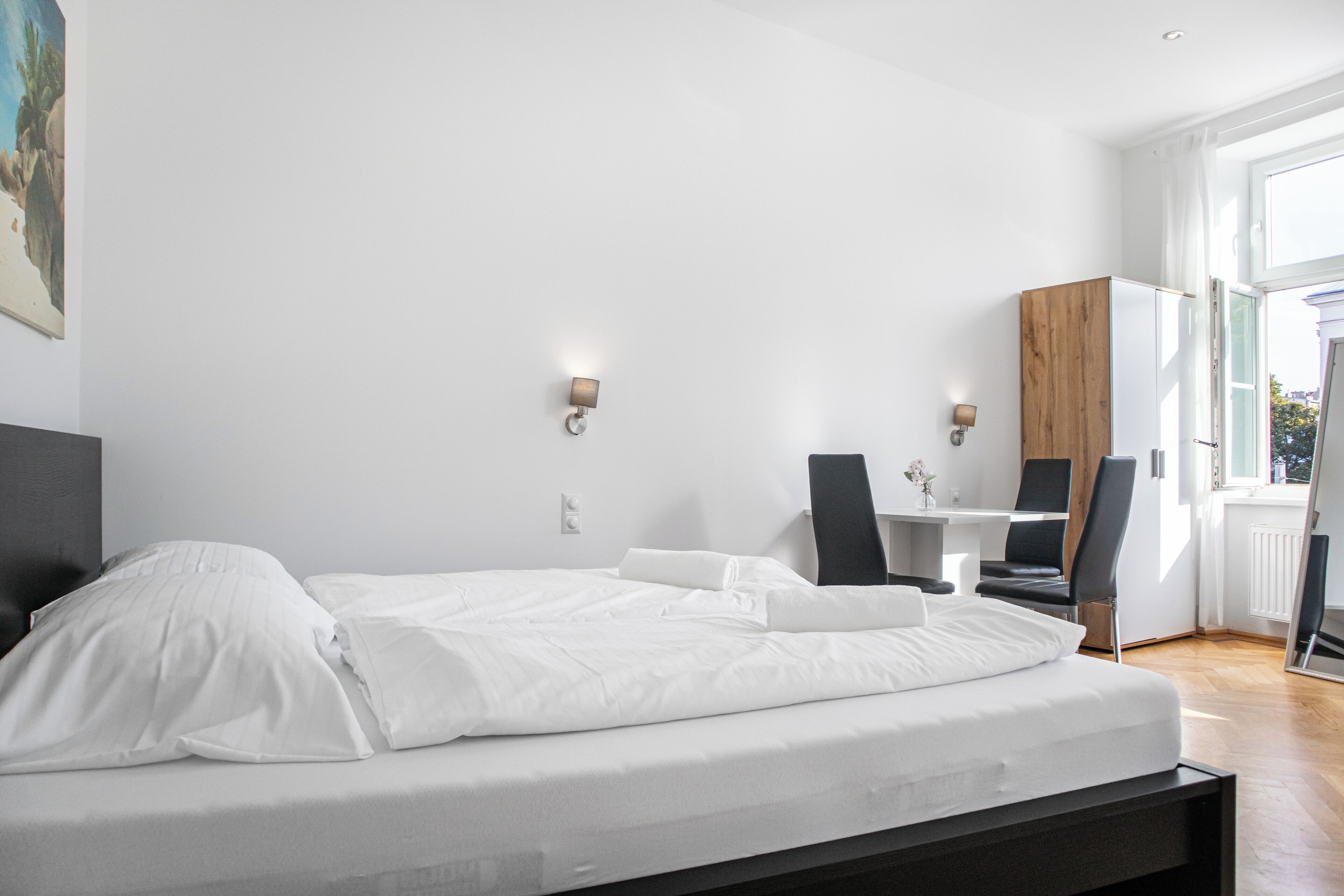 Habitación de hotel moderna con una cama, un escritorio, dos sillas y un ventanal grande.