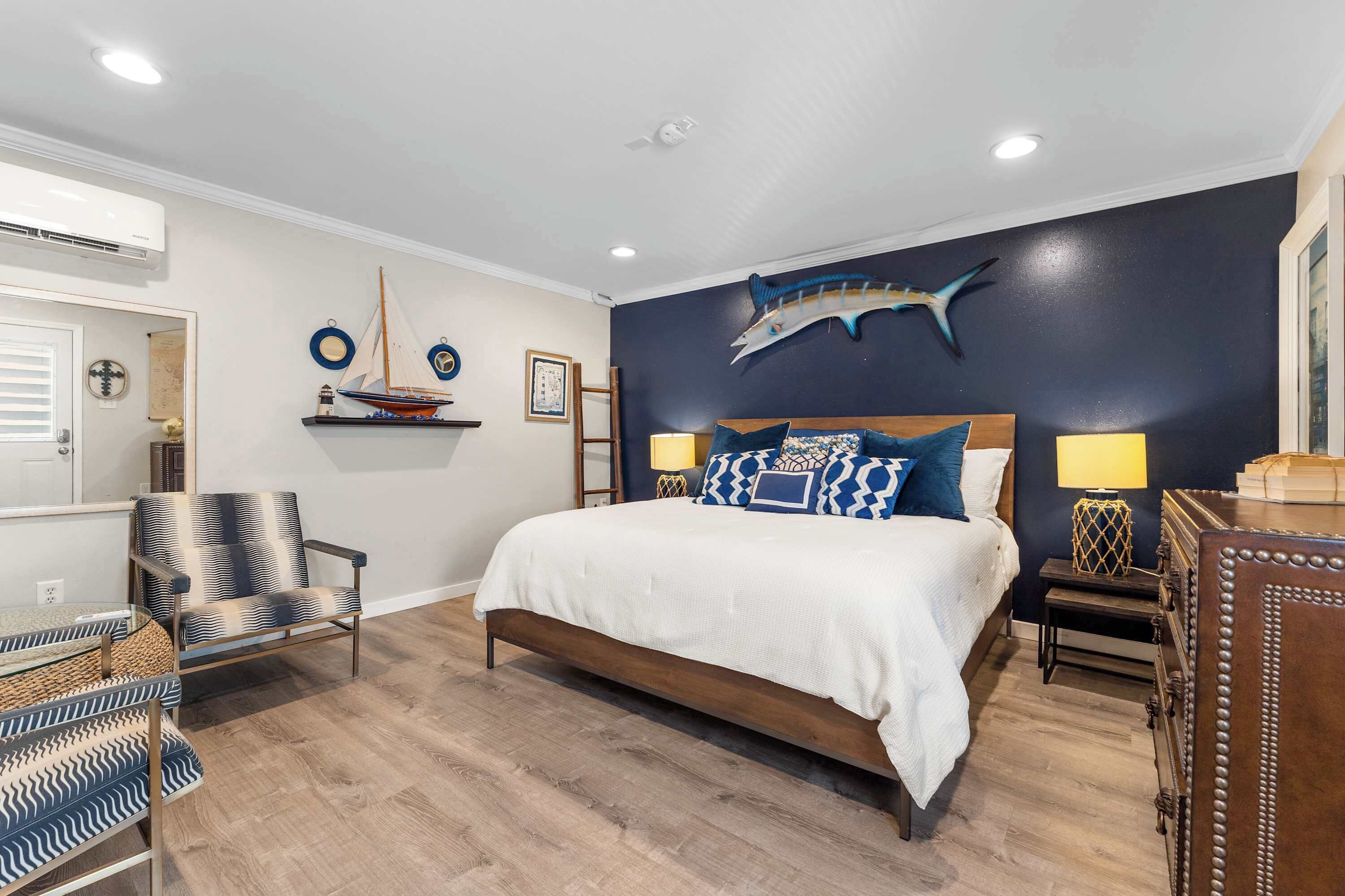 Une chambre à coucher comprenant un lit, une chaise, une table de chevet et une commode.