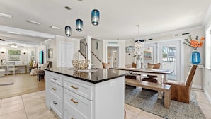 A spacious kitchen with a central island, white cabinetry, and pendant lighting. - Lighthouse Legends-Free Golf Cart-1 Block to Beach (Destin)