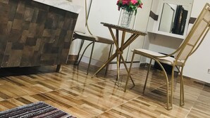A room with a wooden floor, a white sofa, a small round table with a vase of flowers, and two chairs. - Hotel velvet  (Cairo)