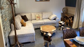 A modern living room with a sectional sofa, a wooden coffee table, a stone wall, and a fireplace.