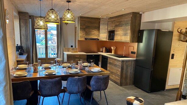 A modern kitchen with a central island, wooden cabinets, and a black refrigerator.
