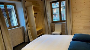 A bedroom with a bed, a chair, a window, and a wooden wall.
