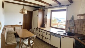 Une cuisine compacte avec une table et un banc en bois, un four encastré et une fenêtre offrant une belle vue.