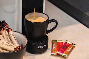 Eine Kaffeemaschine mit einer Tasse Kaffee, eine Schale Schokoladenkekse und eine Packung Speculoos-Kekse.