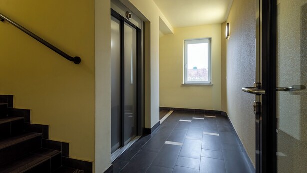 Un couloir avec un escalier, une porte dotée d’une poignée et une fenêtre.