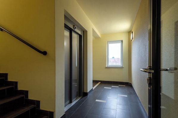 Ein Flur mit Treppe, einer Tür mit Griff und einem Fenster.
