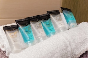 Eine Auswahl an Pflegeprodukten, darunter Shampoo, Duschgel und Körperlotion, präsentiert auf einem weißen Handtuch.
