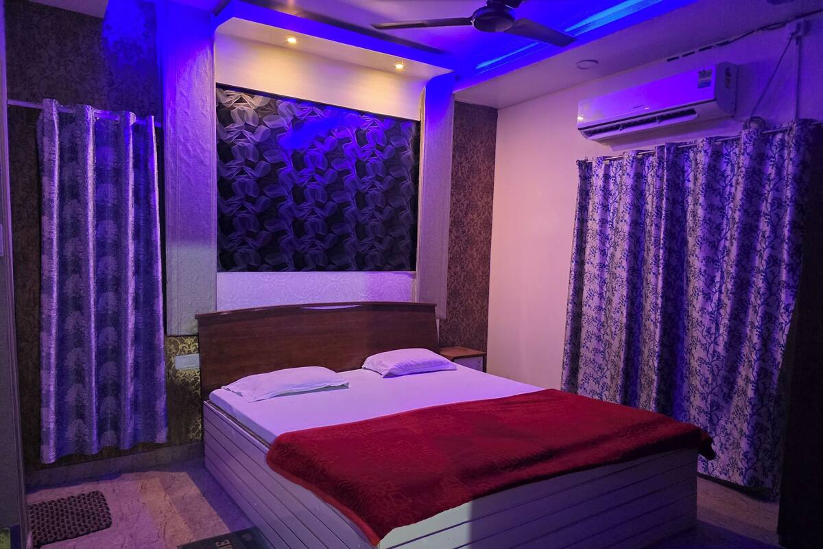 A bedroom with a bed, curtains, a ceiling fan, and an air conditioning unit.