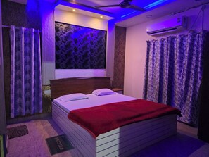 A bedroom with a bed, curtains, a ceiling fan, and an air conditioning unit. - HOTEL ALAKA INN (Puri)