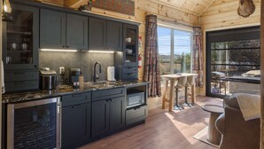 A modern kitchen with dark cabinets, a herringbone backsplash, and a wooden ceiling. - Elk Lodge – Cabin for 4! (Branson)