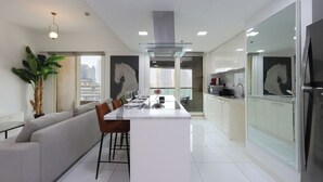 Una cucina moderna con isola centrale, zona pranzo con divano e un'ampia finestra vista città.