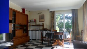 A living room with a checkered floor, wooden furniture, a television, and a dining area with a table and chairs.