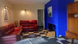 A living room with a checkered floor, a red leather sofa, a wooden cabinet, and a blue accent wall.