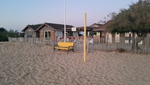 Une plage de sable avec un banc jaune et une clôture en bois.