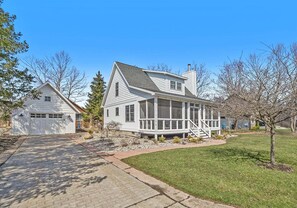 A two-story house with a garage, a covered porch, and a well-maintained lawn.