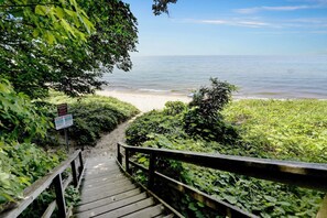 Een houten trap die naar een strand leidt, met een helder uitzicht over de oceaan.