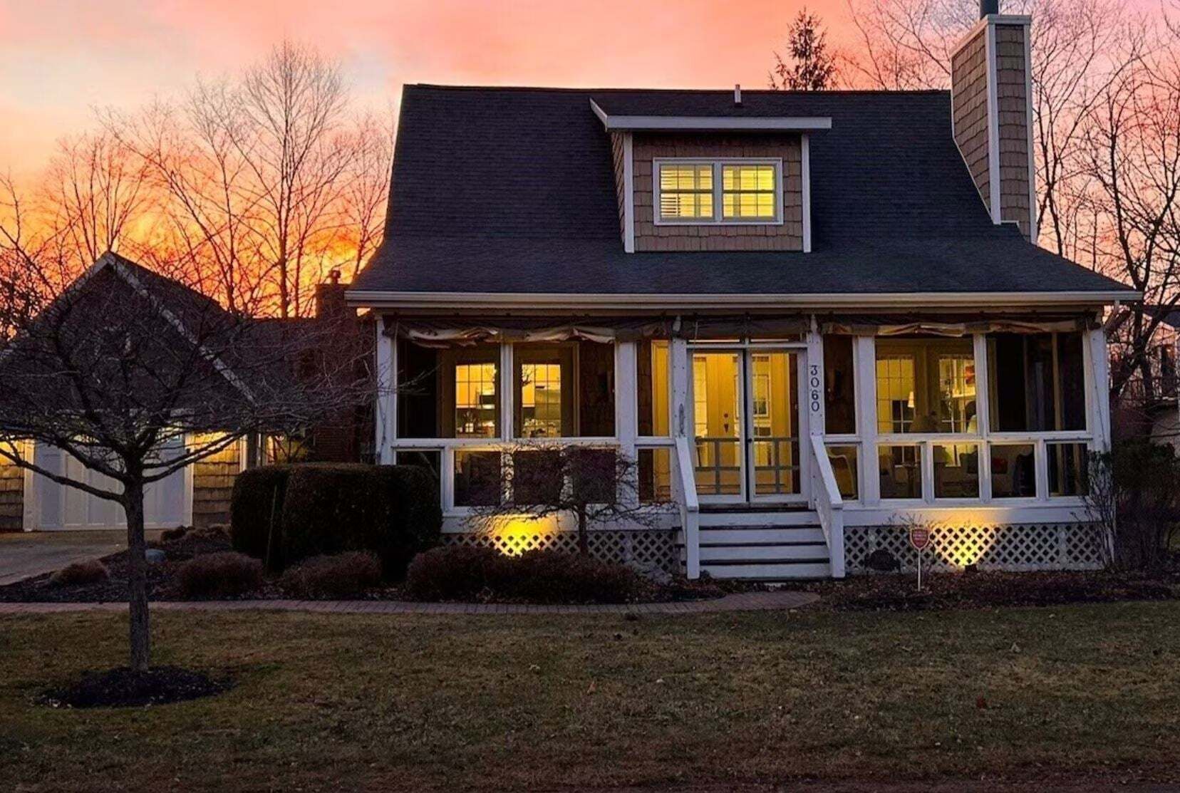 Una casa de dos pisos con un porche, una chimenea y el número 3060 en la fachada.