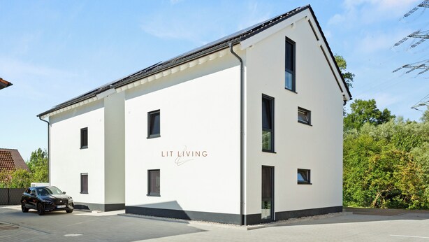 A modern building with a white facade, multiple windows, and a car parked in front. - Lit Living Deluxe Apartments Wörth (Woerth am Rhein)
