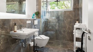 A modern bathroom with a marble floor, a sink, a toilet, and a shower. - Lit Living Deluxe Apartments Wörth (Woerth am Rhein)
