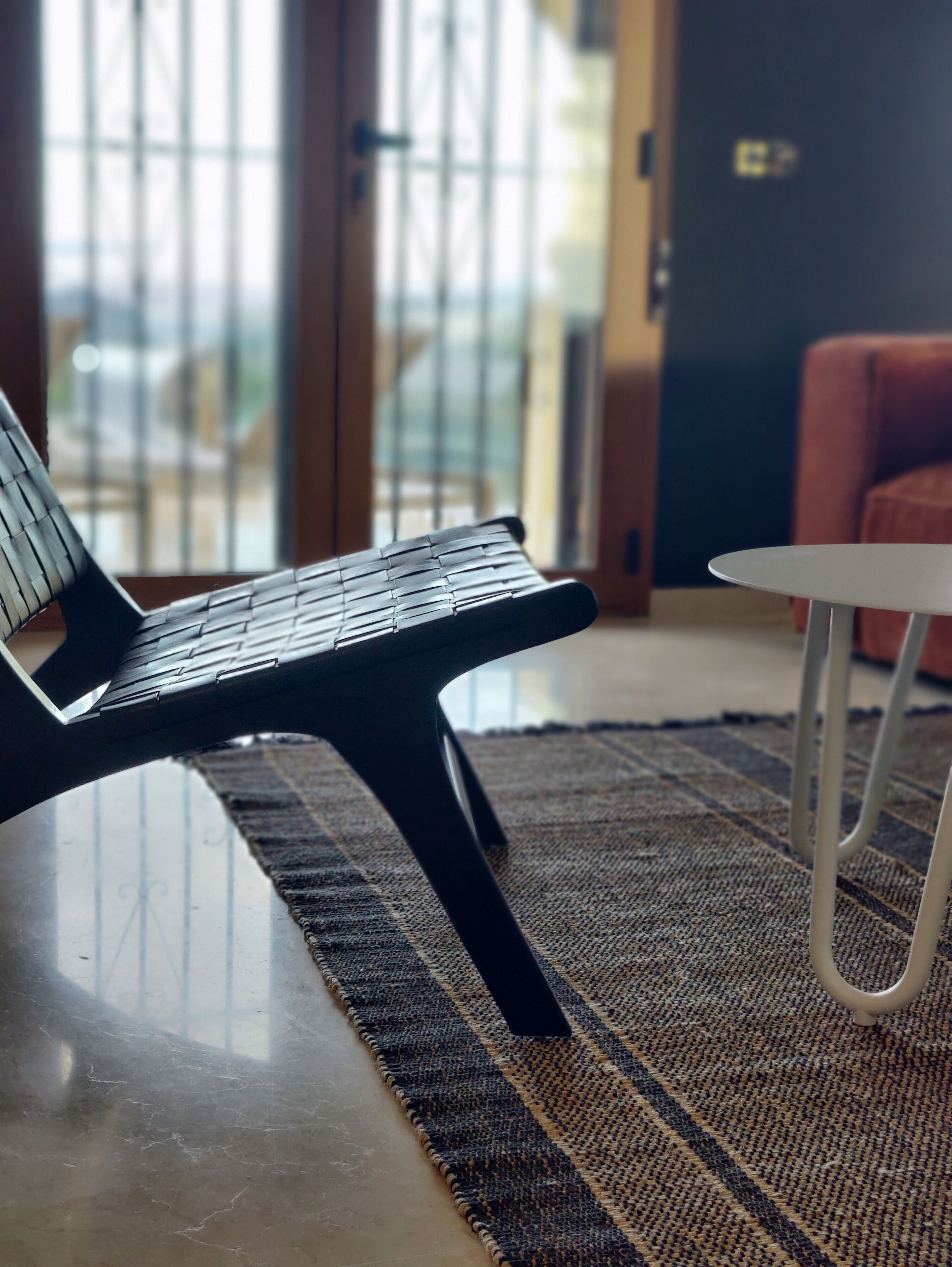 Un salon moderne avec un canapé noir, une table basse blanche et un tapis à motifs.