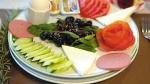 A plate with sliced cucumbers, cheese, olives, a rose-shaped tomato, and meat. - Anamur Çilek Otel (Anamur)