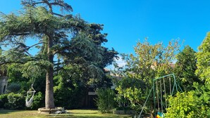 Un patio trasero con una hamaca, un columpio y un árbol grande.