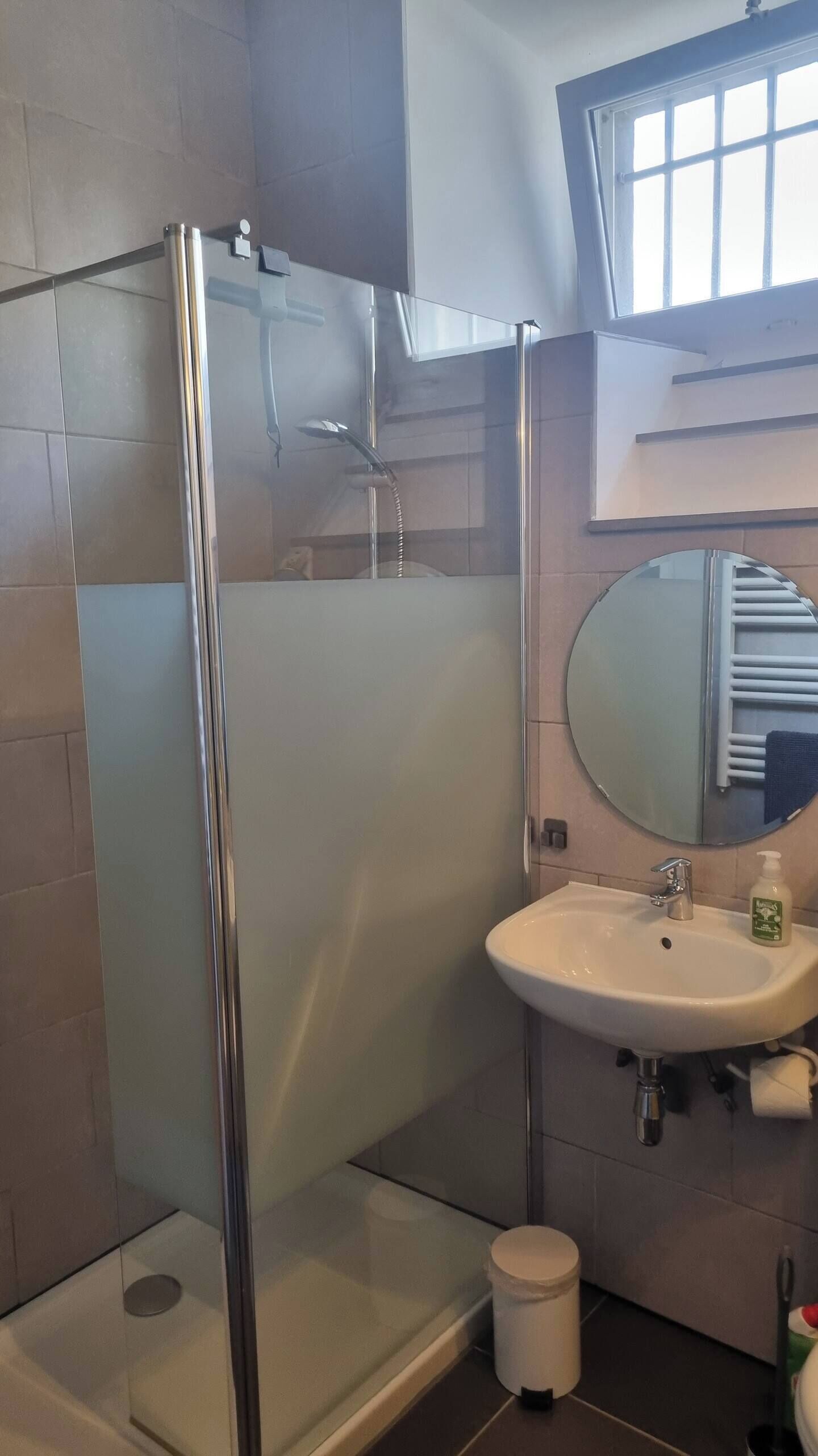 Une salle de bain moderne avec une douche à parois de verre, un lavabo avec un miroir et des toilettes.