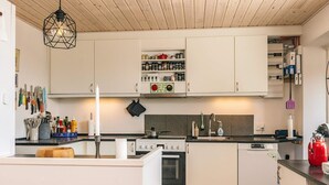 Eine moderne Küche mit weißen Schränken, einem Herd und einem Spülbecken. Verschiedene Küchenutensilien und Geräte sind sichtbar.