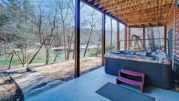 A hot tub in a covered outdoor area with a view of trees and a river. - New! Riverfront Retreat - Sleeps 12, Ellijay (Ellijay)