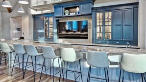A modern kitchen with a large island, bar stools, and blue cabinetry.