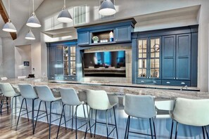 A modern kitchen with a large island, bar stools, and blue cabinetry.