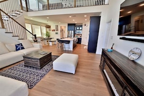 A spacious living area with a staircase, a kitchen, and a dining area.